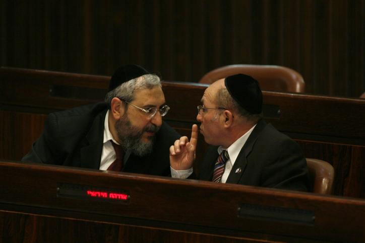 Chaim Amsellem, left, speaks with fellow Shas Party member Avraham Michaeli during a plenum session in the assembly hall in the Israeli Knesset, Feb. 15, 2010. (Miriam Alster/FLASH90/JTA)