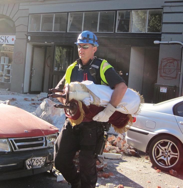 Police Det. Chris Bell retrieves the two Torah scrolls from the Chabad house rubble in Christchurch, March 2, 2011. (Chabad)
