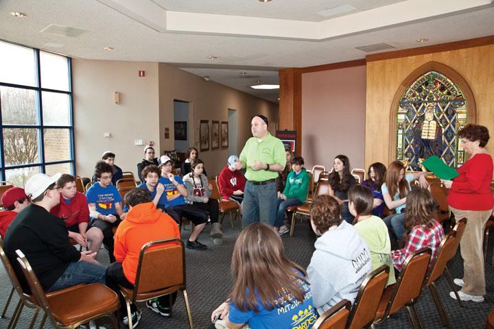 B’nai Amoona’s Assistant Director of Education and Youth Andrew Schwebel briefs students on expectations and behavior during the bus ride to Gateway 180 and during the congregation’s Purim carnival. Photos: Andrew Kerman