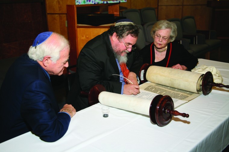 Dr. Phillip and Arleen Korenblat watch Sofer (scribe) Zerach Greenfield 
write the final letters of the Torah at the Solomon Schechter Day School gala marking the school’s 30th anniversary.