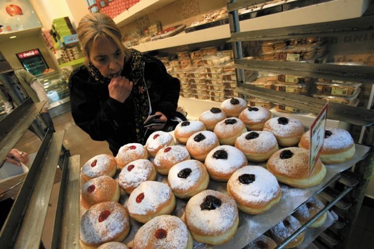 A woman on King George Street in Jerusalem appears perplexed
picking from the array of sufganiyot choices for Hanukkah. Photo:
Nati Shohat/Flash90)
