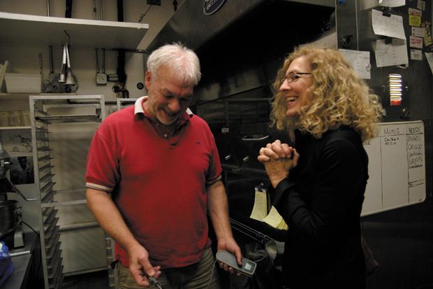 Hank Krussel of Hank’s Cheesecakes in Richmond Heights shows food columnist Margi Lenga Kahn the thermometer the shop uses to check the temperatures of the cheesecakes while they bake in the ovens pictured behind them. 
