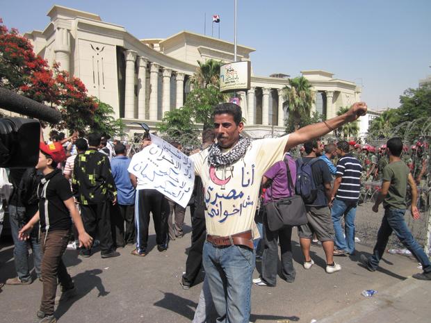 A+protester+outside+Egypt%E2%80%99s+Supreme+Constitutional+Court+in+Cairo+carrying+a+sign+that+reads+%E2%80%9CNo+to+Shafiq+and+to+the+Muslim+Brotherhood+and+down+with+military+rule+too%2C%E2%80%9D+June+14%2C+2012.%C2%A0%0A