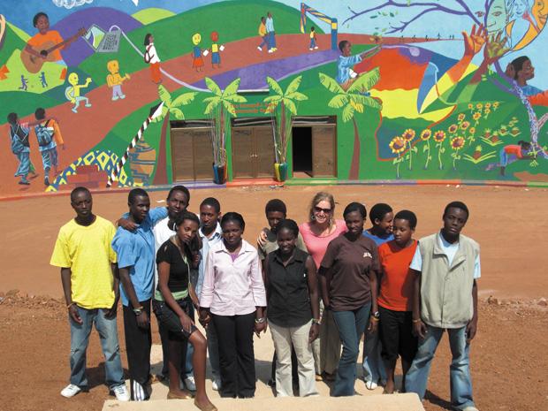 In+the+Agahozo-Shalom+Youth+Village+in+Rwanda%2C+Tanya+Fredman+stands+with+teens+in+front+of+the+mural+they+painted+together.+Fredman+also+led+a+studio+class+for+students+to+create+individual+artwork.%0A