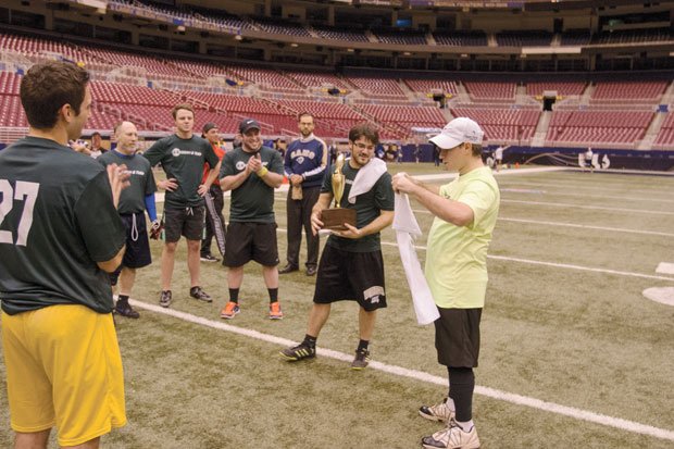 Jason Jacobs (right), president of the Torah &amp; Turf advisory board, presenting the green team with their 2013 Champions T-shirts at the close of the league’s championship game last week at the Edward Jones Dome. Holding the trophy is team quarterback Brian Schwartz. Photo: Mike Sherwin 