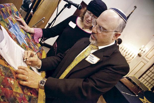 Rabbi Hyim Shafner and wife Sara Winkelman sign the 'post-nuptial' agreement. Photo: Lisa Mandel