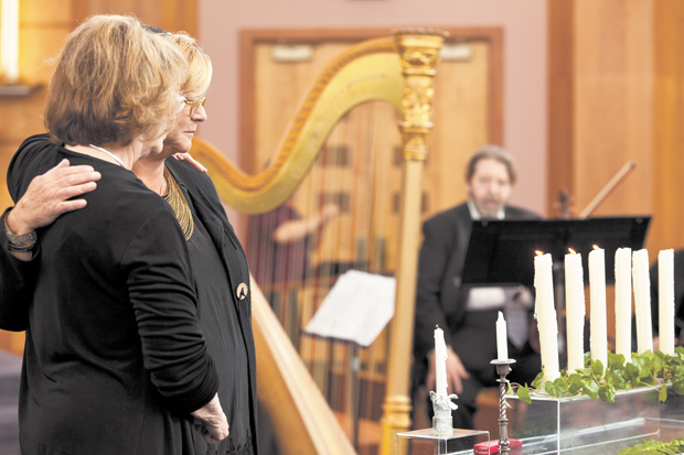 Marcia Goldberg (left) comforts Karen Teckner (daughter of survivor Siegmund Halpern) after lighting a candle during the 2013 Yom HaShoah community commemoration. 