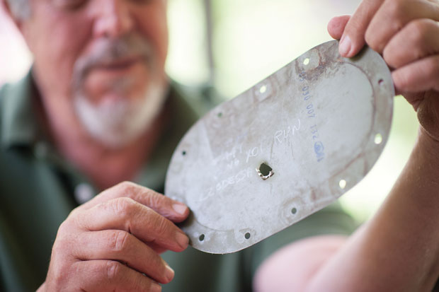 Eric Berla shows a piece of metal from a helicopter he flew with a hole from an AK-47 round during the Vietnam War. The bullet narrowly missed hitting him. 