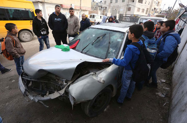 Palestinians in the Qalandiya refugee camp surrounding a car used in an attempted attack on Israeli soldiers, Dec. 16, 2015. (Photo by Flash 90)