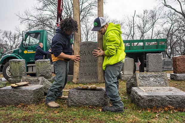 Workers+place+headstones+back+on+their+bases+on+Tuesday+morning+at+Chesed+Shel+Emeth+Cemetery+in+University+City.+More+than+150+monuments+were+knocked+over+Sunday+night.%C2%A0+Photo%3A+James+Griesedieck%C2%A0