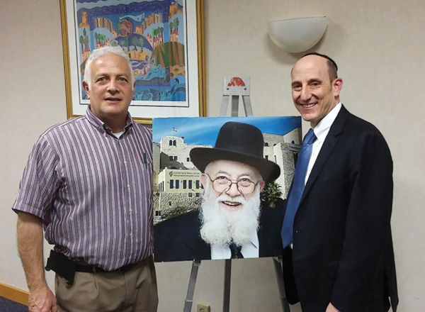 Carl+Wolff+%28left%29+and+Rabbi+Denbo+with+a+photo+of+Rabbi+Noah+Weinberg%2C+z%E2%80%99%E2%80%99l.+Pictured+at+right+are+guests+at+the+dessert+reception+after+Denbo%E2%80%99s+talk.
