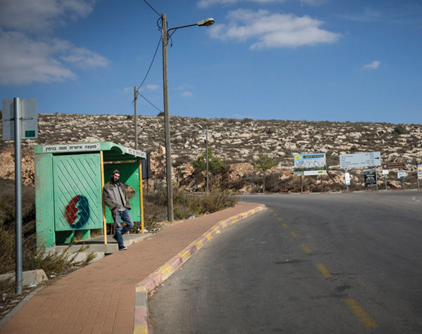 A Jewish man waits at a bus stop near the Israeli settlement of Shiloh in November 2016. The Israeli army evacuated Malachei Hashalom, an unauthorized encampment near Shiloh. Credit: Miriam Alster/Flash90.