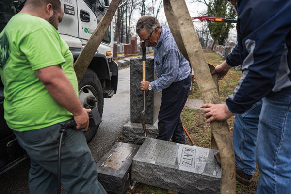 Philip Weiss, president of Rosenbloom Monument Co. (center) works to reset headstones at Chesed Shel Emeth on Feb. 21.  Photo: James Griesedieck