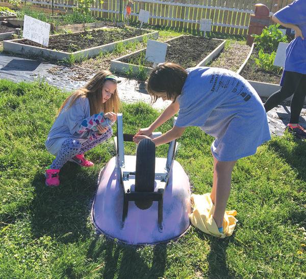 On+April+27%2C+children+in+the+J%E2%80%99s+after-school+program+painted+wheelbarrows%2C+which+were+being+repurposed+as+planters.+Here%2C+Lauren+Whiteford+%28left%29+and+Dylan+Cochran+work+in+the+garden