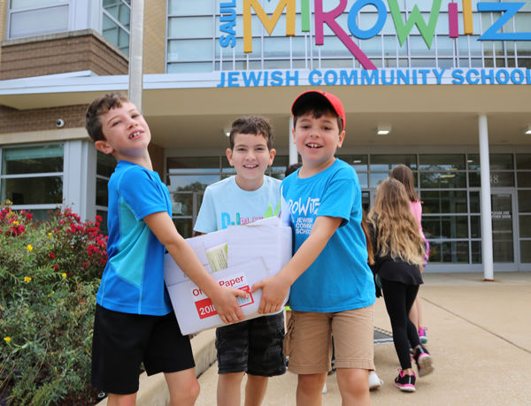 Ben Spector, Ezra Gould and Sam Baron carry a box of donated books.  The third-grade class at Mirowitz spearheaded the book collection effort. 