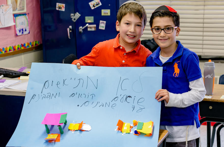 Hillel Torah North Suburban Day School in Skokie, Illinois, provides its students with several hours of fully immersive Hebrew instruction each day. The sign these children are holding reads “We don’t give up. We ask, read and talk until we understand.” (Courtesy of Hillel Torah)