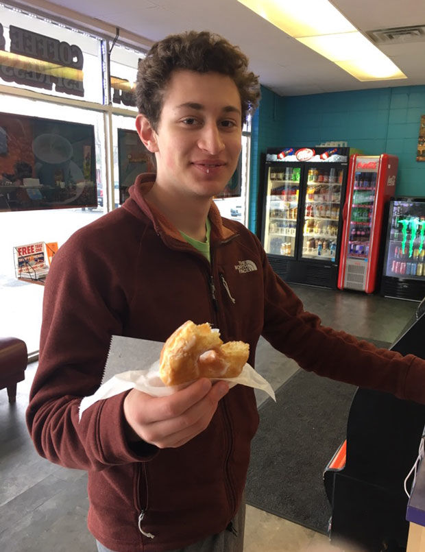 Ethan Beyzer samples a doughnut during his search for top St. Louis doughnuts with fellow student journalist Greg Svirnovsky.