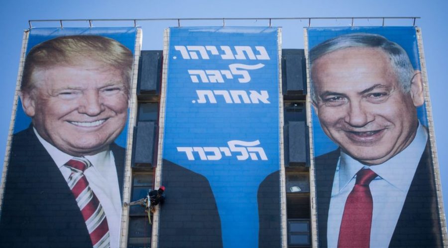 An Israeli worker hangs a campaign billboard of President Donald Trump shaking hands with Prime Minister Benjamin Netanyahu on a Jerusalem building on Feb. 3, 2019. (Yonatan Sindel/Flash90)
