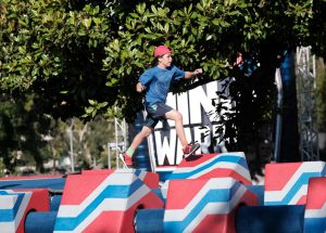 Caption: Jeff Baumgarten, 11, runs across an obstacle that requires running across a series of spinning blocks.  Jeff competes in an episode of “American Ninja Warrior Junior” premiering May 15. Photo by: Eddy Chen/Universal Kids