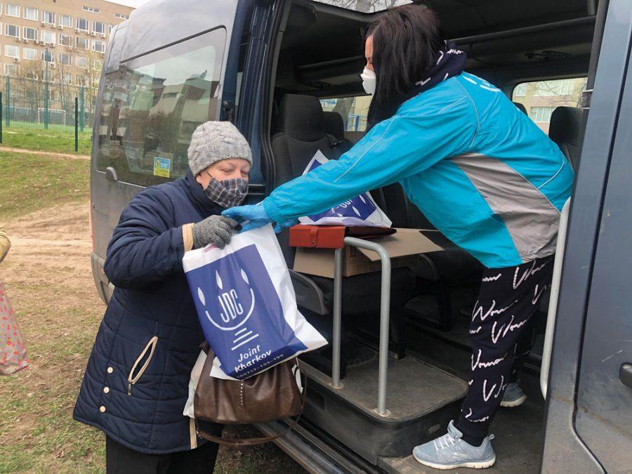A JDC employee, right, delivers an aid package to a Jewish woman in Kharkiv, Ukraine, March 2020.  