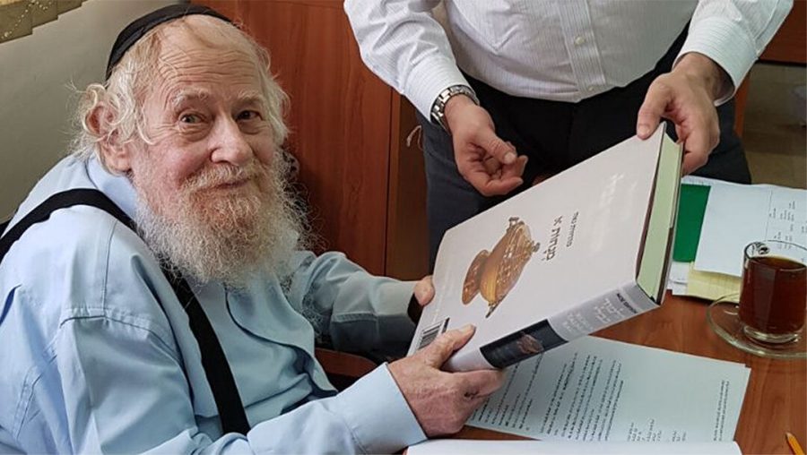 Rabbi Adin Even-Israel Steinzaltz inspects at his Jerusalem home an English-language translation of the Talmud based on his annotations on June 4, 2018. (Wikimedia Commons/SoInkleined)