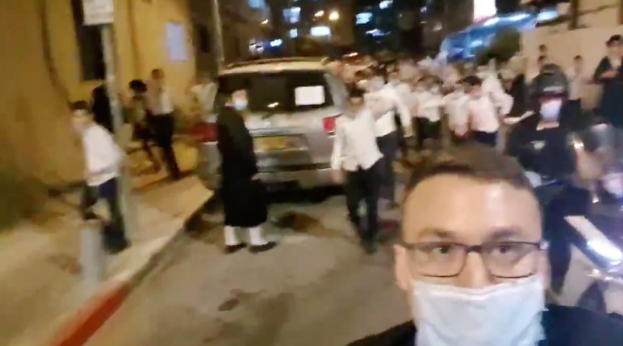 In Bnei Brak, Israel, reporter Ittai Shickman films himself chased by a mob of haredi Orthodox Jews while standing outside the home of a prominent rabbi. (Screenshot from Twitter)