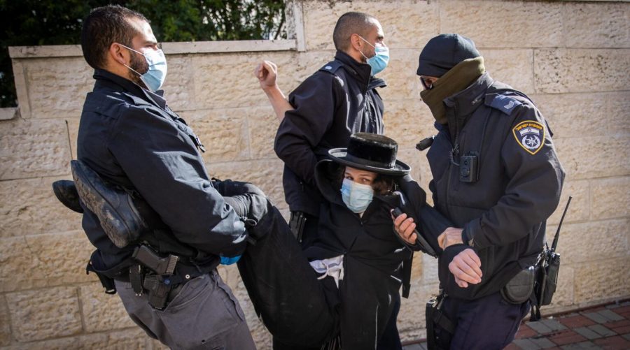Police officers carry away a protester during a raid on a Jerusalem yeshiva that remained open in violation of COVID-19 restrictions, Jan. 19, 2021. (Yonatan Sindel/Flash90) 
