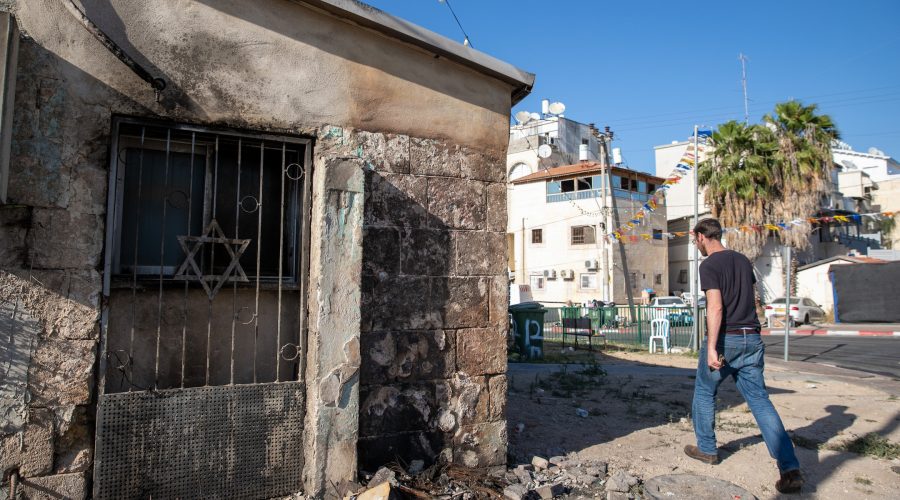 A man walks next to a synagogue that was set on fire in the central Israeli city of Lod following a night of violent protests, May 14, 2021. (Yossi Aloni/Flash90)
