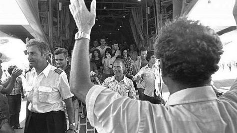 Israeli Foreign Minister Yigal Allon (back to camera) welcoming the rescued Air France passengers and crew, including pilot Michel Bacos (left), coming off an Israel Air Force Hercules plane at Ben-Gurion International Airport, July 1976. Credit: Moshe Milner/Israel Government Press Office.