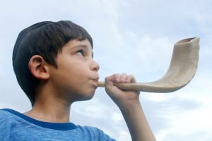 Boy blowing a shofar for Rosh Hashana