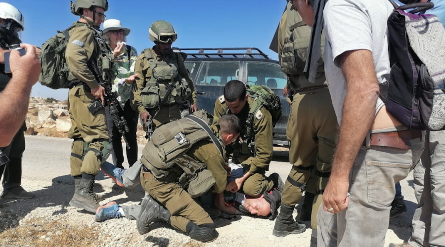 An IDF officer kneels on the neck of activist Tuly Flint in the West Bank on Sept. 17, 2021. (Courtesy of Combatants for Peace)