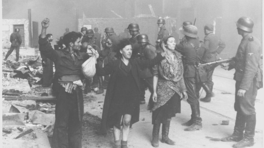 SS troops guard members of the Jewish resistance captured during the suppression of the Warsaw ghetto uprising. Picture between 19 April 1943 and 16 May 1943 taken at Nowolipie street looking East, near intersection with Smocza street. In the back one can see ghetto wall with a gate. (US Holocaust Memorial Museum/Wikimedia Commons)
