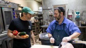 Lenny Kohn (at left) talks with AJ Moll in the kitchen at Kohn’s earlier this month. Moll was shadowing Kohn, learning about the day-to-day operations at the kosher deli and market. Photo: Mike Sherwin