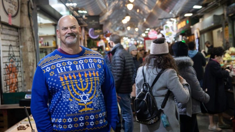 An+American+Jewish+man+wears+a+sweder+with+the+Star+of+David+and+a+lit+Hannukkia+%28Menorah%29+during+the+Jewish+holiday+of+Hanukkah%2C+at+the+Mahane+Yehuda+Market+in+Jerusalem%2C+on+December+25%2C+2019.+Photo+by+Hadas+Parush%2FFlash90+%2A%2A%2A+Local+Caption+%2A%2A%2A+%D7%99%D7%A8%D7%95%D7%A9%D7%9C%D7%99%D7%9D+%D7%97%D7%A0%D7%95%D7%9B%D7%94+%D7%AA%D7%99%D7%99%D7%A8+%D7%AA%D7%99%D7%99%D7%A8%D7%99%D7%9D+%D7%9E%D7%A0%D7%95%D7%A8%D7%94+%D7%97%D7%A0%D7%95%D7%9B%D7%99%D7%99%D7%94+%D7%A9%D7%95%D7%A7+%D7%9E%D7%97%D7%A0%D7%94+%D7%99%D7%94%D7%95%D7%93%D7%94%0A