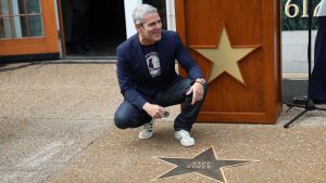Andy Cohen kneeling with is new Star on the St. Louis Walk of Fame.