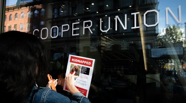A woman affixes a flier for Israeli hostages to Cooper Union College in New York City, a day after Jewish students sheltered in a library during a pro-Palestinian protest, Oct. 26, 2023. 