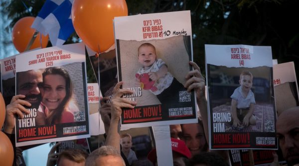 Israelis hold photographs of the Bibas family, and orange balloons, at a press conference calling for the release of 10-month-old Kfir, 4-year-old Ariel, and their parents Shiri and Yarden. at Hostage Square in Tel Aviv, Nov. 28, 2023. 