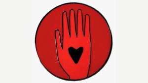 Each Artists4Ceasefire pin resembles a glossy red quarter, with an image of a hand surrounding a small black heart.
Credit...Artists4Ceasefire