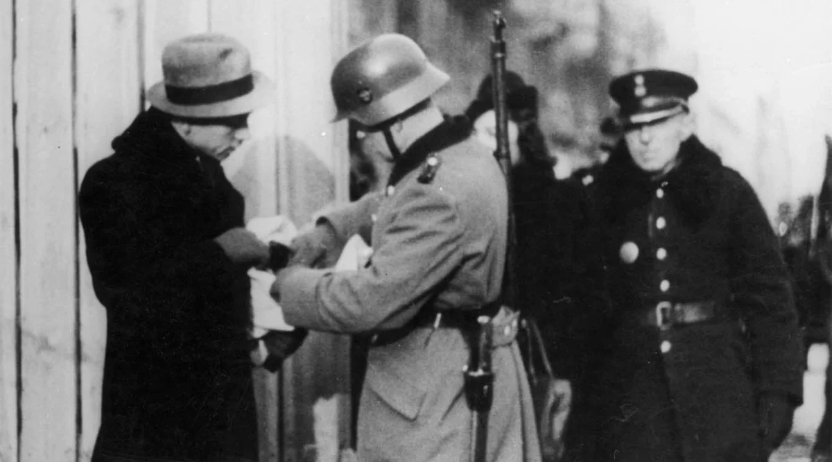 Polish and German police officers inspect the papers of a Jewish pedestrian, Warsaw, 1941. 