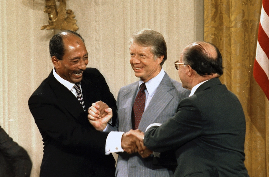 Egyptian President Anwar Sadat, left, U.S. President Jimmy Carter, center, and Israeli Prime Minister Menachem Begin shaking hands at the conclusion of the Camp David Peace Accords signing ceremony in the East Room of the White House, Sept. 17, 1978. (Wikimedia Commons)
