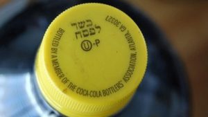 A kosher-for-Passover bottle of Coca-Cola, distinguished from ordinary Coca-Cola bottles by its yellow cap and special "hechsher." Credit: Mark H. Anbinder via Flickr.com.