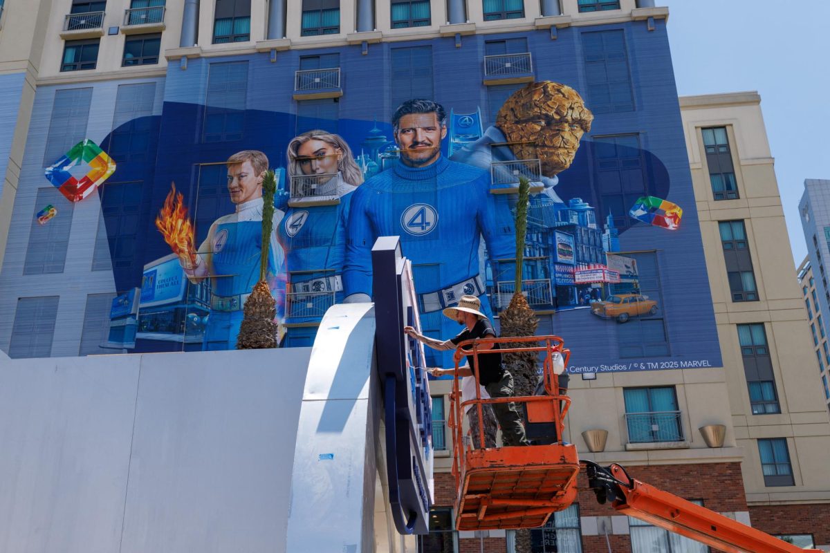 Workers paint and outdoor display next to a hotel wrapped in a Fantastic Four movie advertisement as San Diego prepares to host thousands of visitors for Comic-Con International, in San Diego, California, U.S. July 22, 2025.  REUTERS/Mike Blake