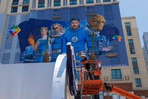 Workers paint and outdoor display next to a hotel wrapped in a Fantastic Four movie advertisement as San Diego prepares to host thousands of visitors for Comic-Con International, in San Diego, California, U.S. July 22, 2025.  REUTERS/Mike Blake