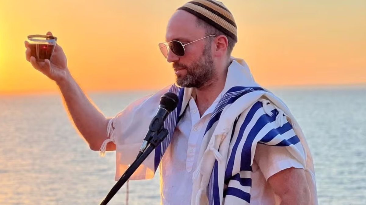 At sunset by the water, Rabbi Ari Yehuda Saks leads a blessing with wine in hand and tallit draped over the shoulders (Courtesy / Moti Dolgin)