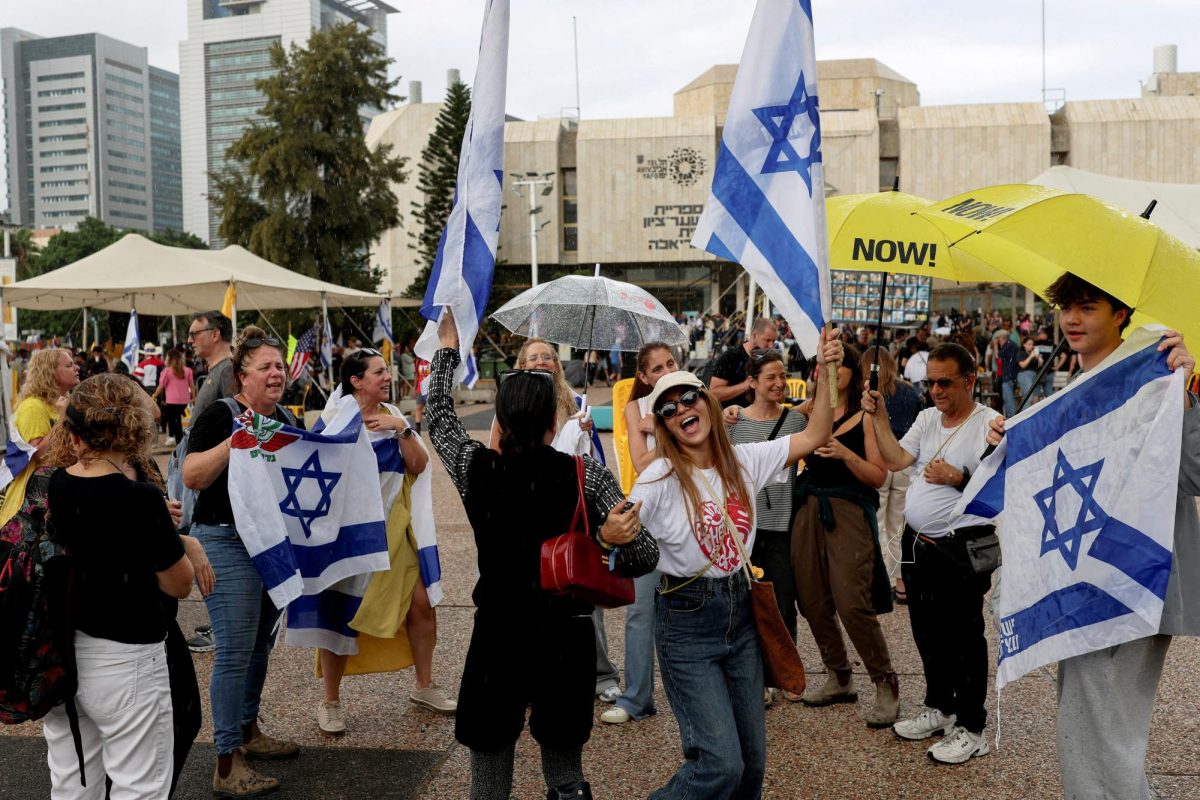 People celebrate holding Israeli flags after U.S. President Donald Trump announced that Israel and Hamas agreed on the first phase of a Gaza ceasefire, at the "Hostages square", in Tel Aviv, Israel, October 9, 2025. REUTERS/Ronen Zvulun     TPX IMAGES OF THE DAY