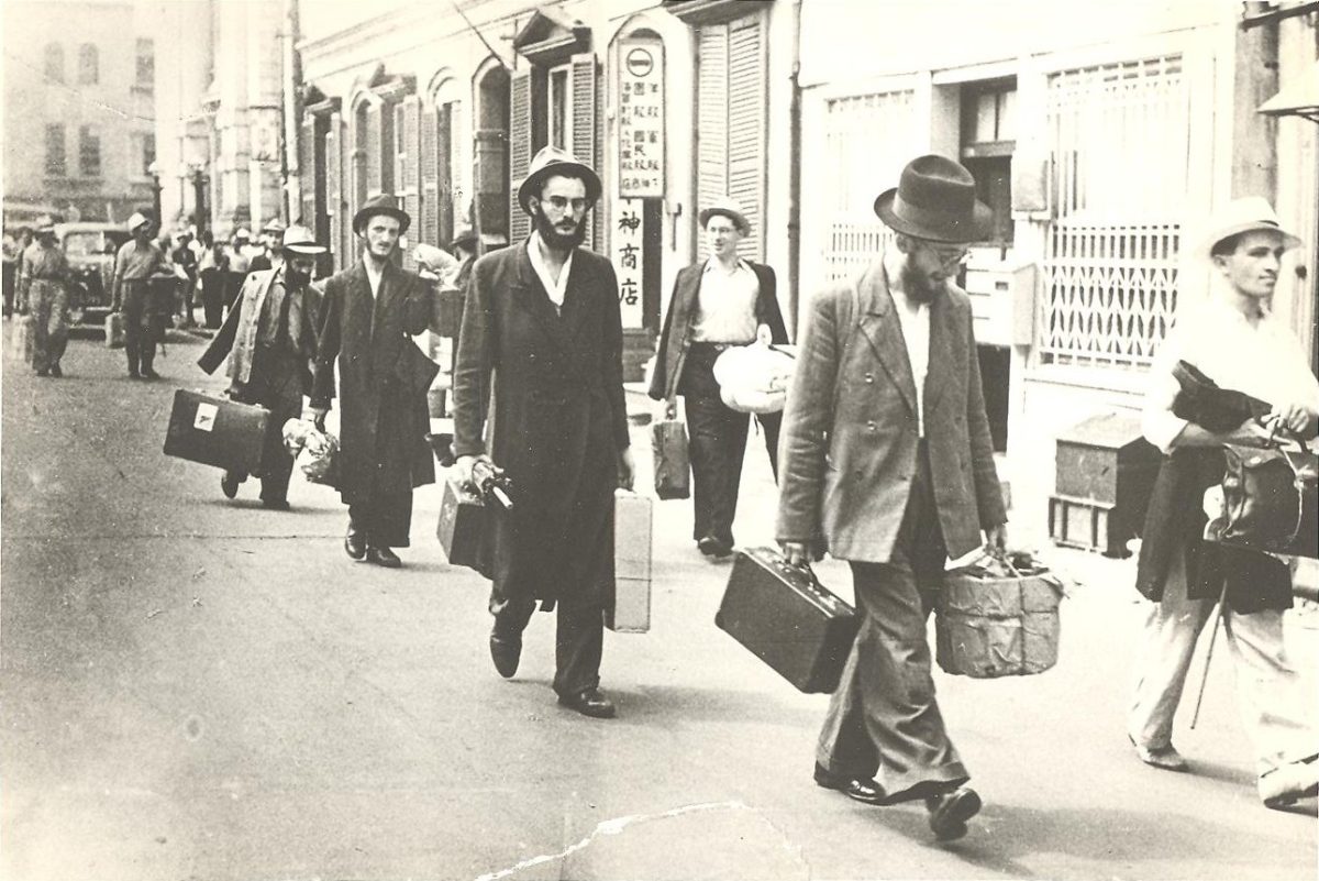 Avraham Tzvi Landa, center with umbrella, arrives in Kobe, Japan, with fellow yeshivah students.