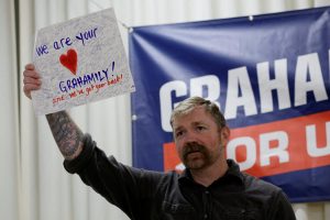 Democratic candidate for U.S. Senate Graham Platner holds up a handmade card given to him by an audience member reading 'We Are your Grahamily And We've Got Your Back!' during a campaign town hall meeting in Portland, Maine, U.S., June 7, 2026. REUTERS/Brian Snyder