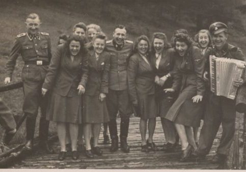 Women’s auxiliaries and SS officers enjoy music not far from the barracks of Auschwitz-Birkenau. 
