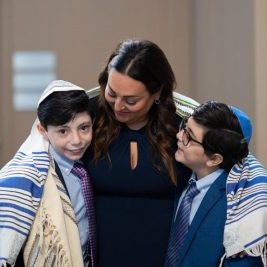 The Abeles family wrapped in Eli's tallit that he wore on his bar mitzvah 30+ years ago. Photo: Spoonful of Sugar Photography
